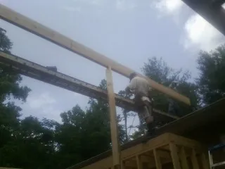 Carpenter setting a ridge beam over a new addition frame — Ice Dam Removal by Roofing Brothers in Neilton