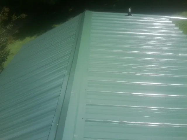 New green metal panels meeting at the ridge of a roof — Flat Roof Repair work by our crew in Neilton