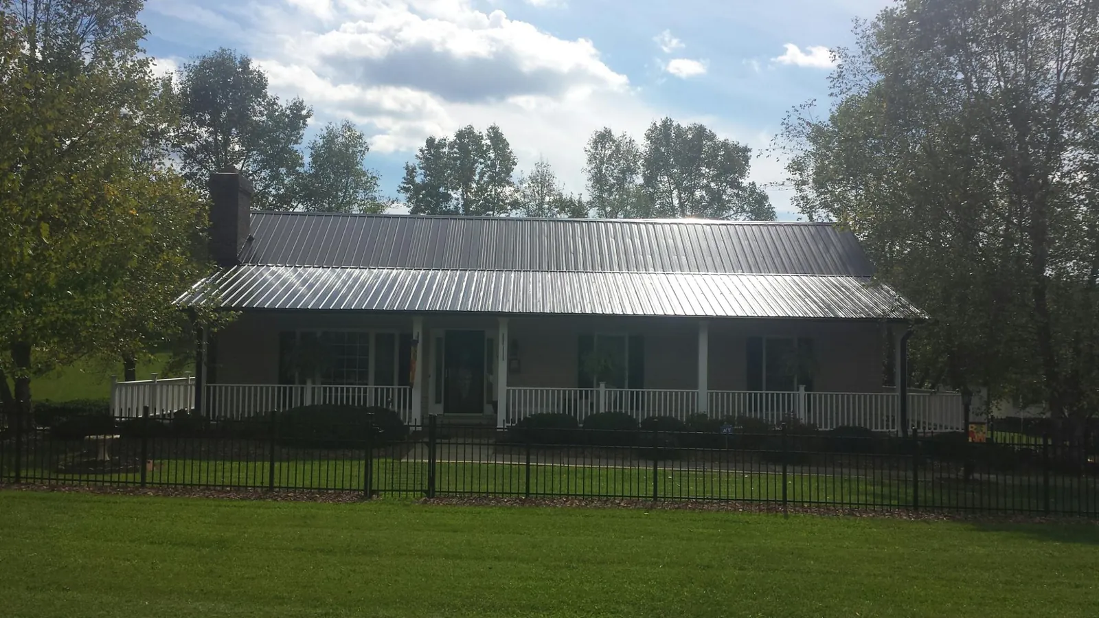 Gray metal roof on a brick ranch with a full width front porch — Gutter Guard Installation work by our crew in Neilton
