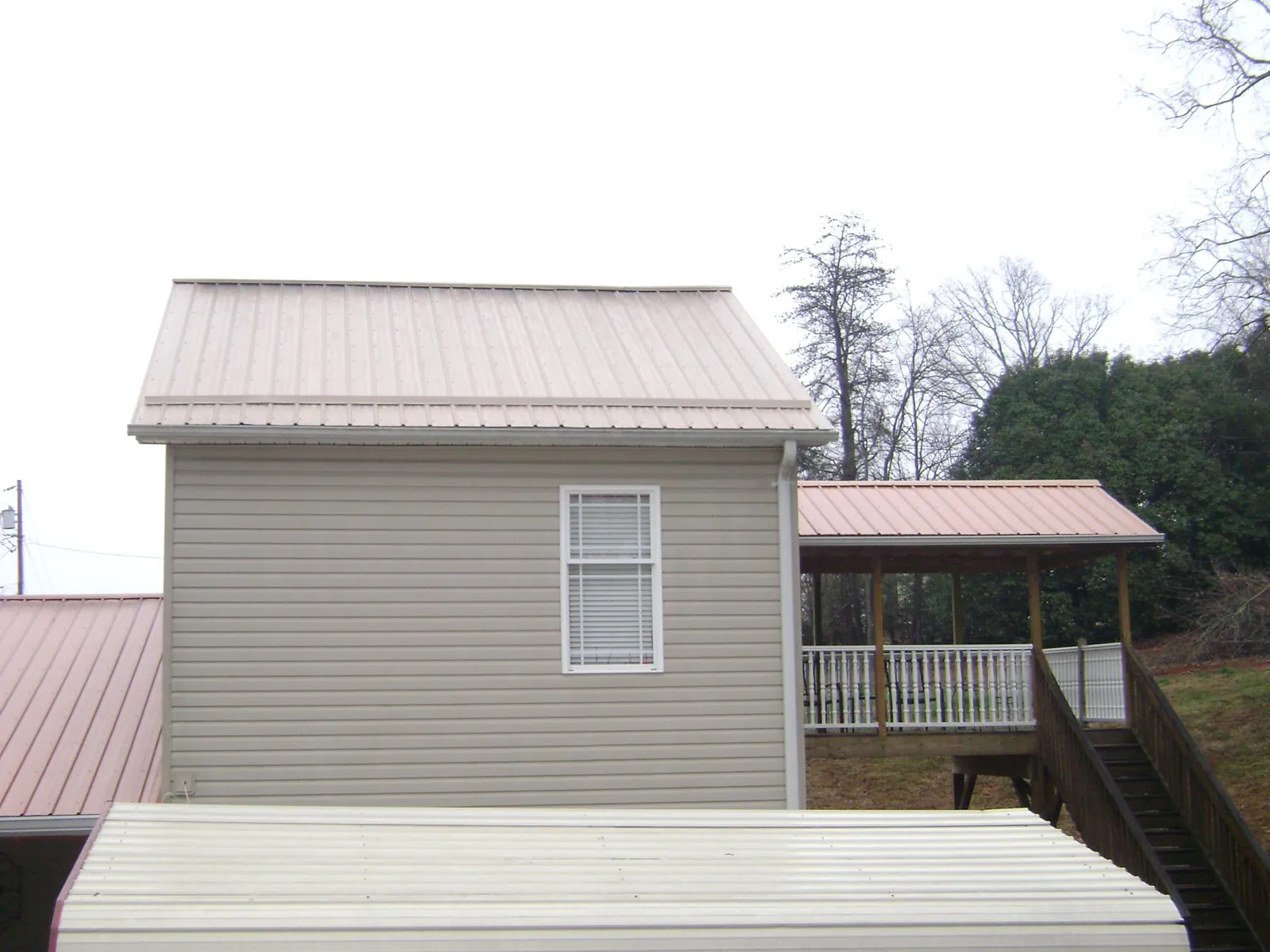 Tan metal roofs on a two story addition and attached porch, from a Roof Replacement job in Neilton