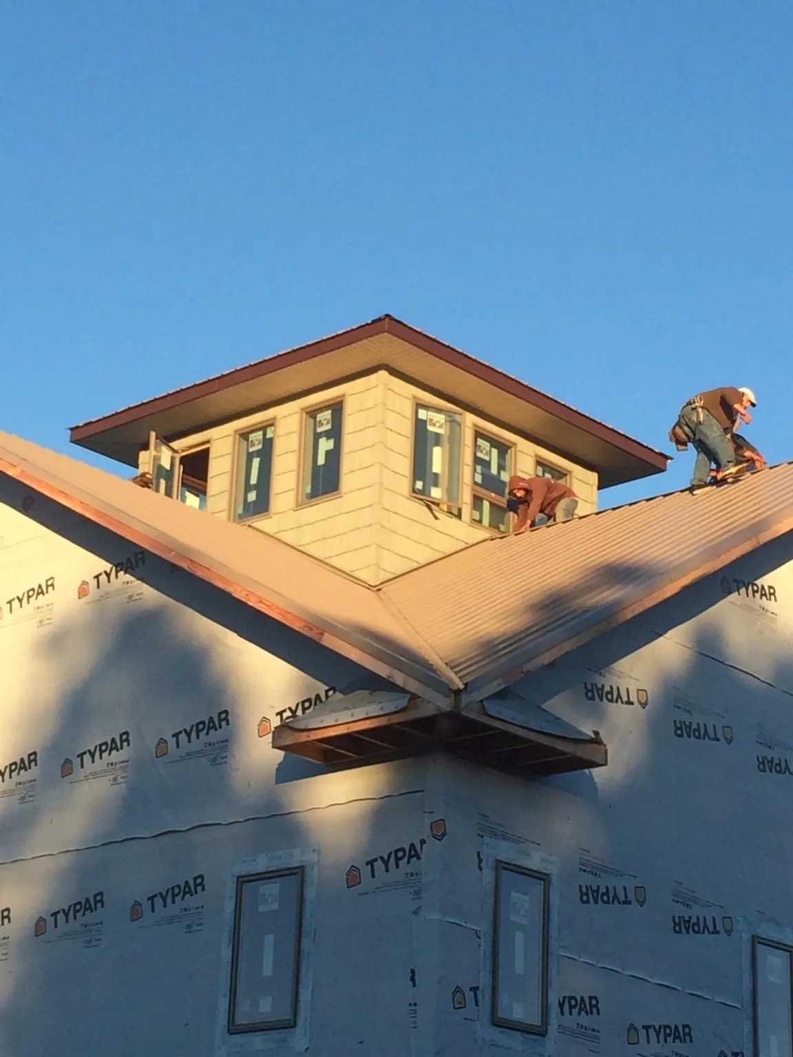 Roofers working around a rooftop cupola on a new metal roof at sunset — Roof Waterproofing in Neilton by Roofing Brothers